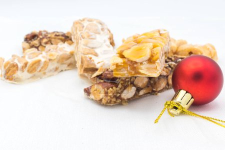 Téléchargez les photos : Différents types de turrn (nougat), un bonbon de Noël traditionnel en Espagne, avec une décoration de Noël (une boule de Noël rouge ou boule), sur un fond blanc. - en image libre de droit