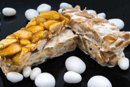 Photo for Different types of turrn (nougat), a traditional Christmas sweet in Spain, isolated on a black surface, with some sugared almonds. - Royalty Free Image