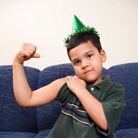 Photo for Boy in party hat flexing arm muscle. - Royalty Free Image