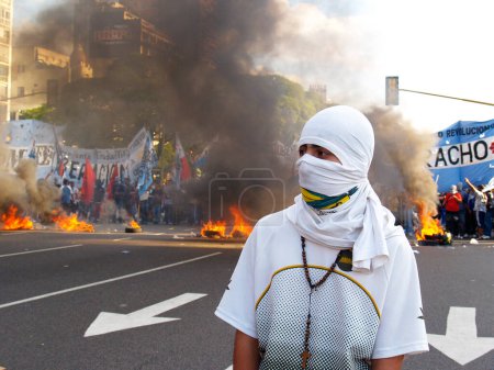 Téléchargez les photos : Jeune homme dans le masque contre les pneus brûlants en arrière-plan - en image libre de droit