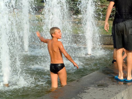 Téléchargez les photos : Enfants jouant avec l'eau dans la fontaine dans le parc - en image libre de droit