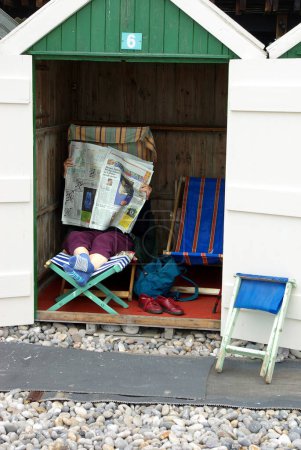Téléchargez les photos : Personne lisant le journal dans Beach Cabin - en image libre de droit