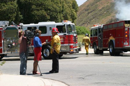 Téléchargez les photos : Pompier donnant une interview à la chaîne d'information locale - en image libre de droit