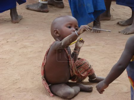 Téléchargez les photos : Masai enfant assis sur le sable - en image libre de droit