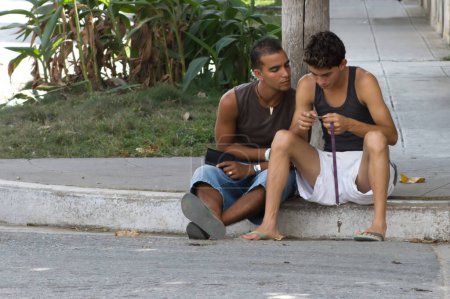 Téléchargez les photos : Deux jeunes hommes assis sur le trottoir - en image libre de droit