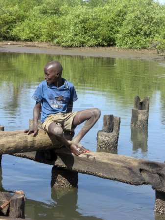 Téléchargez les photos : Garçon assis sur le pont Koto en Gambie Afrique de l'Ouest - en image libre de droit