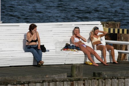 Téléchargez les photos : People sitting on bench on sea promenade - en image libre de droit