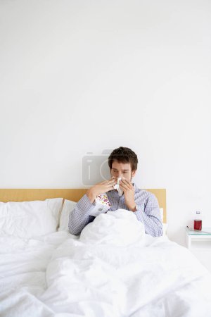 Téléchargez les photos : "Homme au lit avec un froid qui se mouche" - en image libre de droit