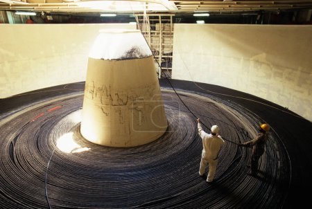 Foto de Trabajadores parados en una gigantesca bobina de cable - Imagen libre de derechos
