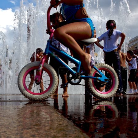 Foto de Joven chica a caballo bicicleta en el fondo de la fuente - Imagen libre de derechos