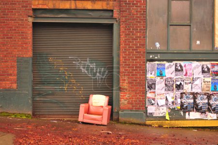 Foto de Pared de ladrillo, carteles y una silla roja rota - Imagen libre de derechos
