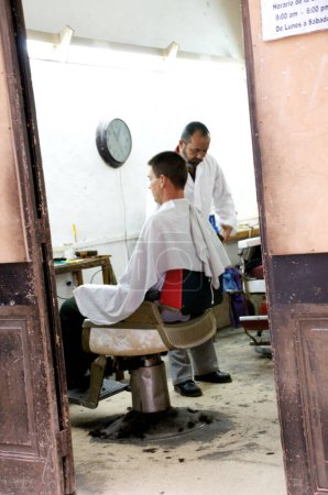 Foto de Un peluquero masculino corta un pelo en una peluquería - Imagen libre de derechos