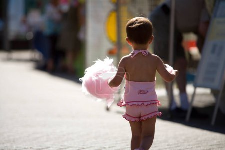 Téléchargez les photos : Petite fille en vêtements roses marchant dans la rue - en image libre de droit