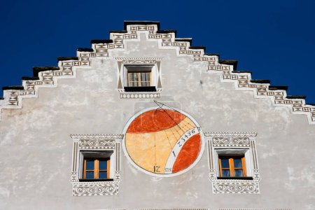 Téléchargez les photos : Cadran solaire rouge et orange sur le mur de la maison européenne - en image libre de droit
