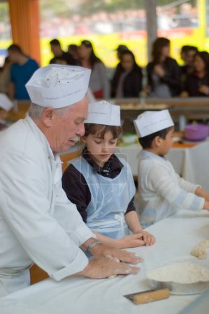 Téléchargez les photos : The Show of bread in Paris, 2010. Vieux boulanger enseigne aux enfants à faire du pain - en image libre de droit