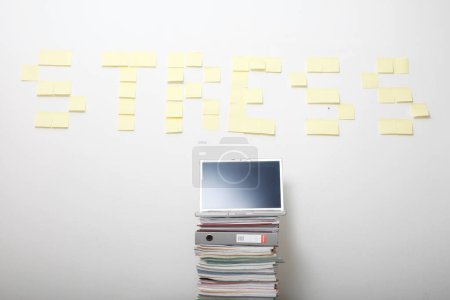 Téléchargez les photos : Stress sur le mur avec pile de documents et ordinateur portable - en image libre de droit