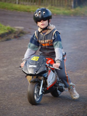 Téléchargez les photos : Petit garçon en casque chevauchant une moto - en image libre de droit