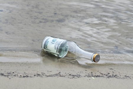 Photo for Bottle With Money on sea shore - Royalty Free Image