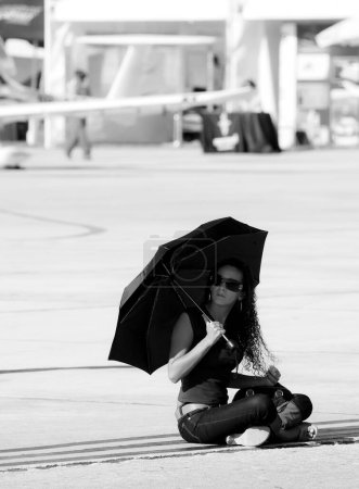 Téléchargez les photos : Femme assise avec un parapluie sur le fond - en image libre de droit