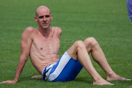 Téléchargez les photos : Jeune homme athlétique assis sur l'herbe - en image libre de droit