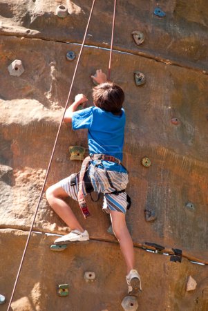 Téléchargez les photos : Garçon escalade un mur en plein air centre d'escalade - en image libre de droit