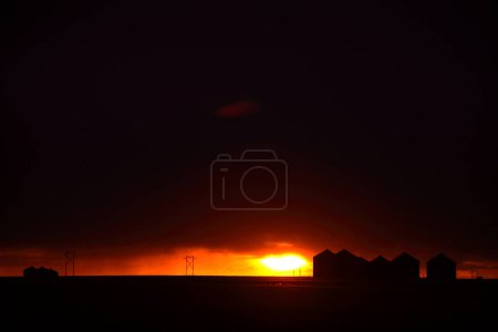 Foto de Puesta de sol detrás de graneros metálicos en Saskatchewan - Imagen libre de derechos