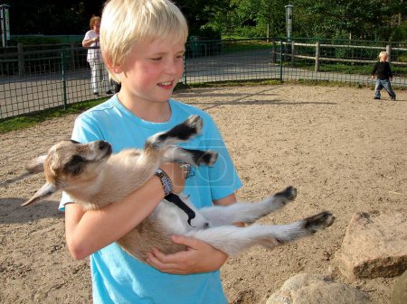 Téléchargez les photos : Style de vie scandinave - garçon tenant une chèvre - en image libre de droit
