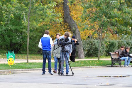 Téléchargez les photos : Opérateur avec une caméra vidéo dans la rue en automne - en image libre de droit