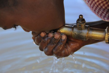 Téléchargez les photos : Enfant africain eau potable du robinet d'eau, vue rapprochée - en image libre de droit