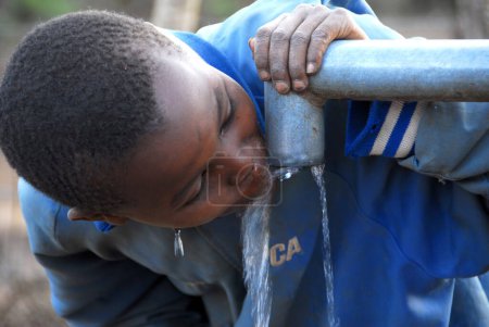 Téléchargez les photos : Enfant africain eau potable de la pompe à eau - en image libre de droit