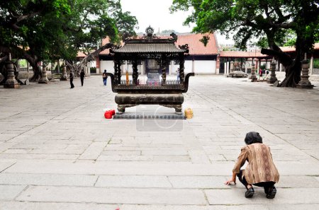 Photo for An old woman prays to a small shrine - Royalty Free Image