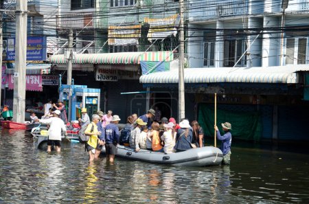 Téléchargez les photos : Transport de personnes dans les rues inondées - en image libre de droit