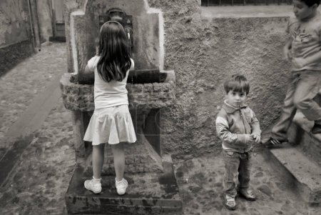 Téléchargez les photos : Enfants à la fontaine d'eau en plein air en Italie - en image libre de droit