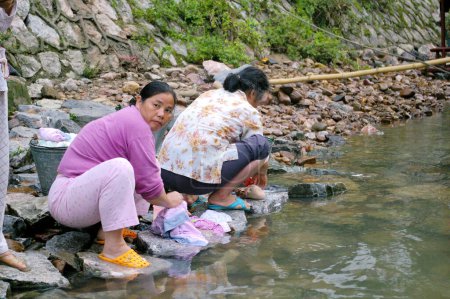 Foto de Mujeres chinas lavando ropa a lo largo del río por la mañana - Imagen libre de derechos