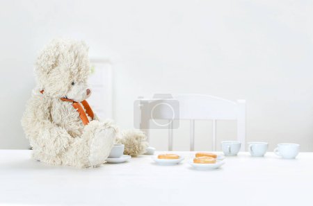 Téléchargez les photos : L'ours en peluche boit du thé avec des bagels à table
. - en image libre de droit