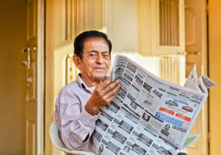 Photo for Senior Indian gent reading local newsprint - Royalty Free Image