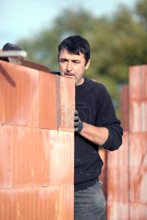 Téléchargez les photos : Tradesman construire un mur de bâtiment - en image libre de droit