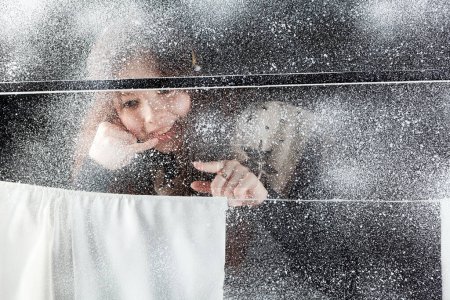 Téléchargez les photos : Fille sourit dans la fenêtre d'hiver - en image libre de droit
