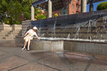 Photo for Woman sitting on fountain - Royalty Free Image