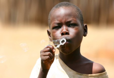 Photo for Portrait of African boy blowing soap bubbles - Royalty Free Image