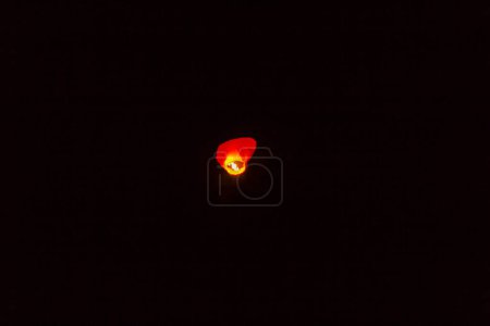 Téléchargez les photos : Petite lampe volante isolée sur fond sombre - en image libre de droit