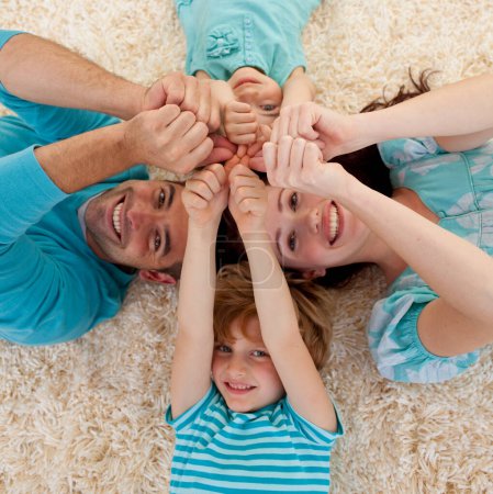Téléchargez les photos : Angle élevé de la famille sur le sol avec les têtes et les mains ensemble - en image libre de droit