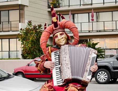 Photo for Harlequin accordionist playing on the street - Royalty Free Image