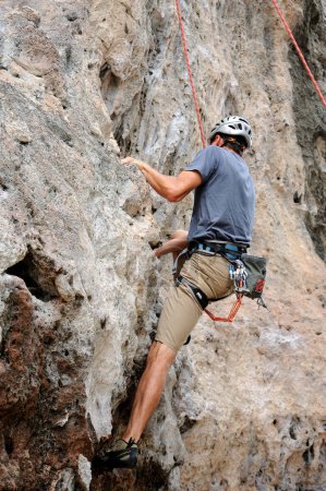 Foto de Hombre escalador aferrado a un acantilado - Imagen libre de derechos