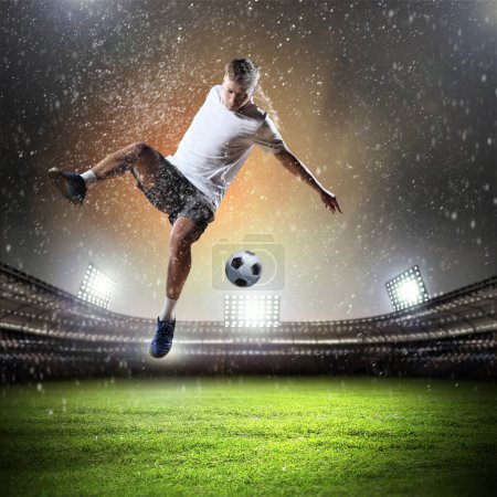 Foto de Joven jugador de fútbol con pelota en el fondo del estadio - Imagen libre de derechos