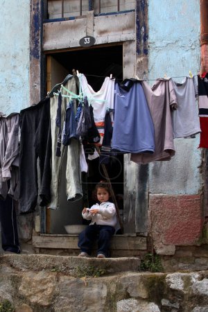 Téléchargez les photos : Jeune fille assise à la porte de la maison familiale à Valparaiso - en image libre de droit