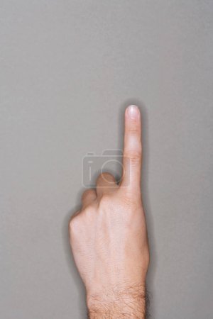 Téléchargez les photos : Gros plan du doigt pointant vers le haut sur fond gris - en image libre de droit