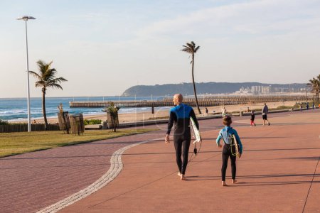 Téléchargez les photos : Surfing Father and Son walking on promenade - en image libre de droit