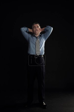 Téléchargez les photos : Homme d'affaires inquiet posant sur fond noir - en image libre de droit