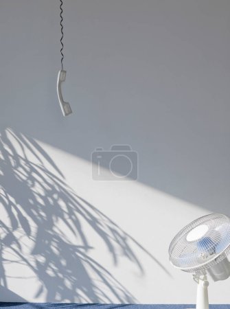 Photo for View of a telephone receiver and fan in an empty room - Royalty Free Image